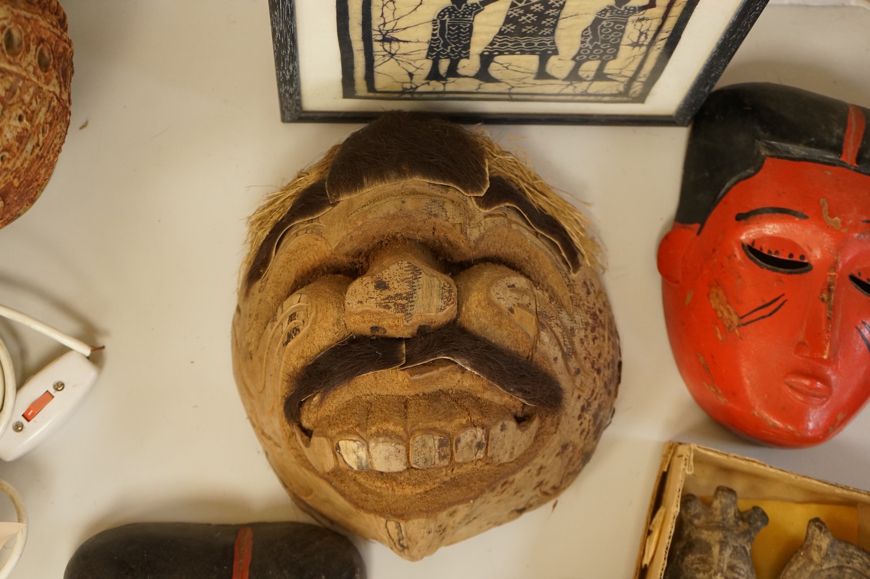 Four Japanese masks, two small oil lamps and a framed batik-16.5high x 19cm wide